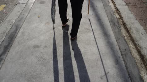 Back-view-of-a-disabled-woman-walk-with-support-stick